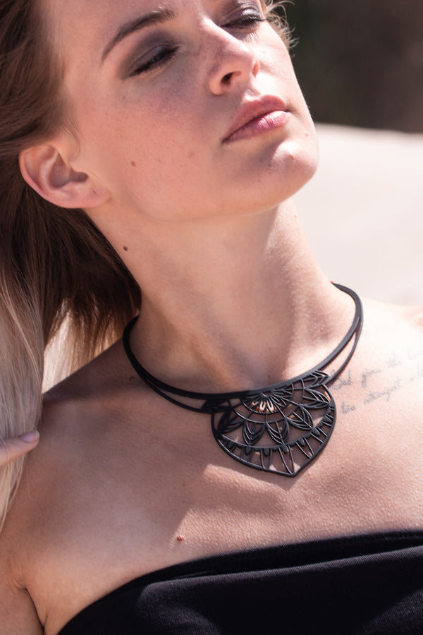 zoom, vue gros plan, collier mandala, couleur noir. Vue taille réelle, porté par mannequin dorine gaudin. Bijoux fantaisies en silicone, ladygum, marque française, créateurs, designers. Style plastron, fleur, nature, floral, lotus, nénuphar, zen, yoga, pétales, feuilles, géométriques, carré, losanges, motifs, dentelle, tribal, ethnique. Léger, souple, résistant à l'eau/à la chaleur/à la lumière. Collier ajustable, longueur réglable, fermoir en T. Cadeau original.