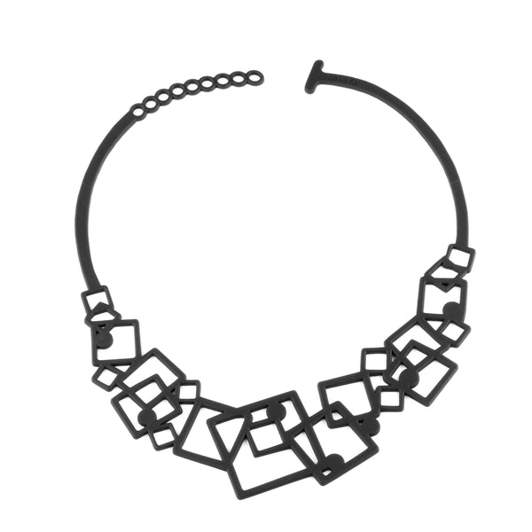 vue collier tétris, à plat, en entier. Noir, silicone, ladygum, bijoux fantaisies, marque française, créateurs, designers. Style carré, graphique, cubique, géométrique, contemporain, plastron. Souple, léger, minimisant les allergies, résistant à l'eau, à la chaleur. Longueur réglable, collier tétris ajustable, fermoir en T.